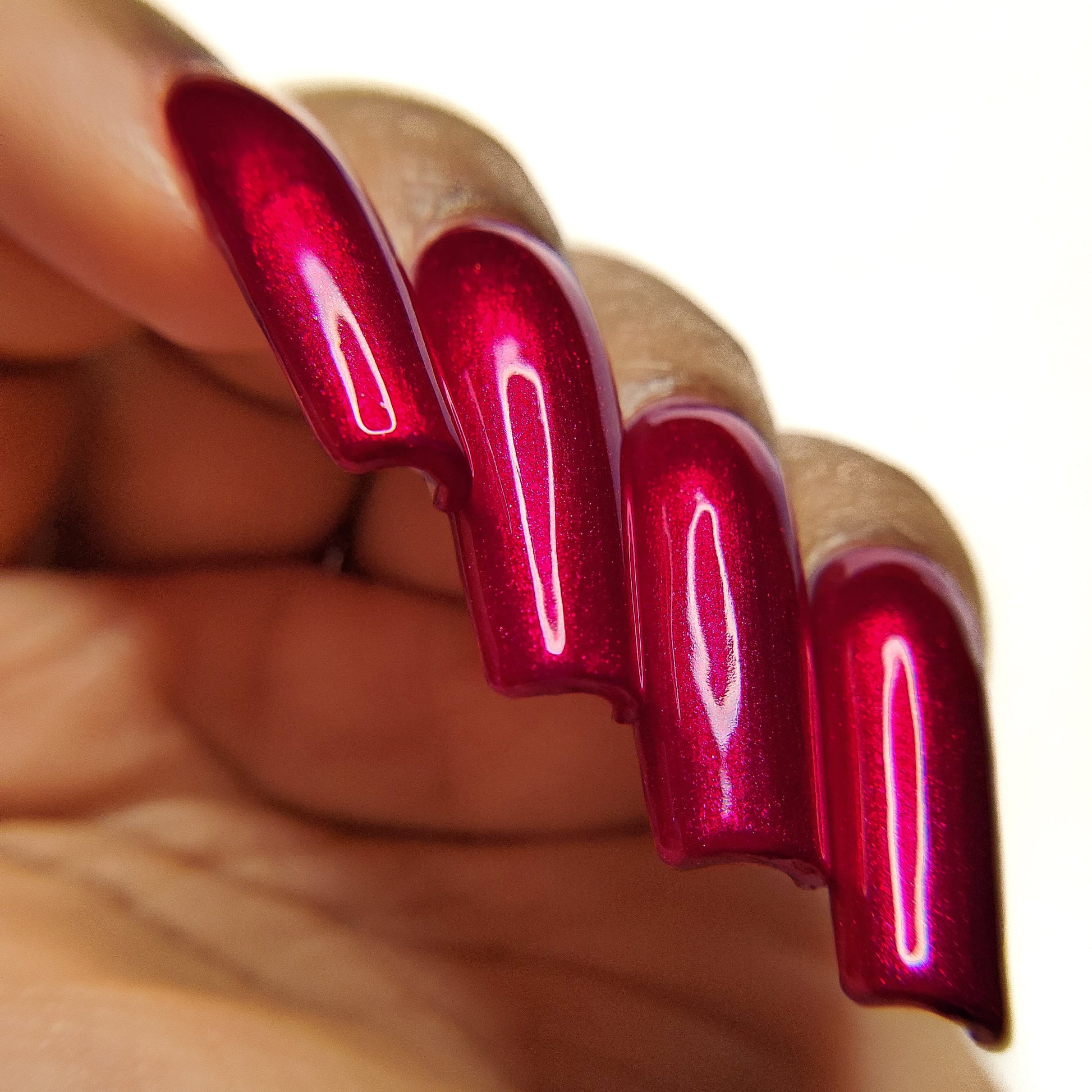 Close-up of a hand with red nail polish on a white background